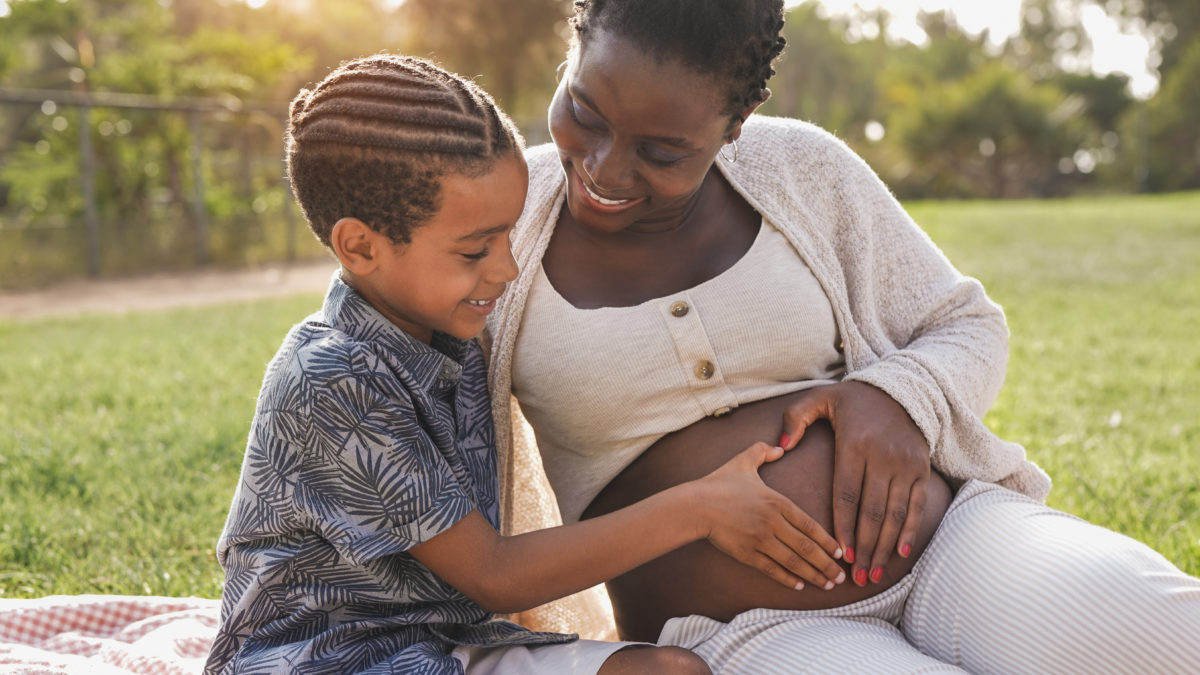 African pregnant mother and mixed race son touching belly