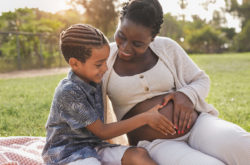 African pregnant mother and mixed race son touching belly