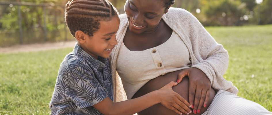 African pregnant mother and mixed race son touching belly