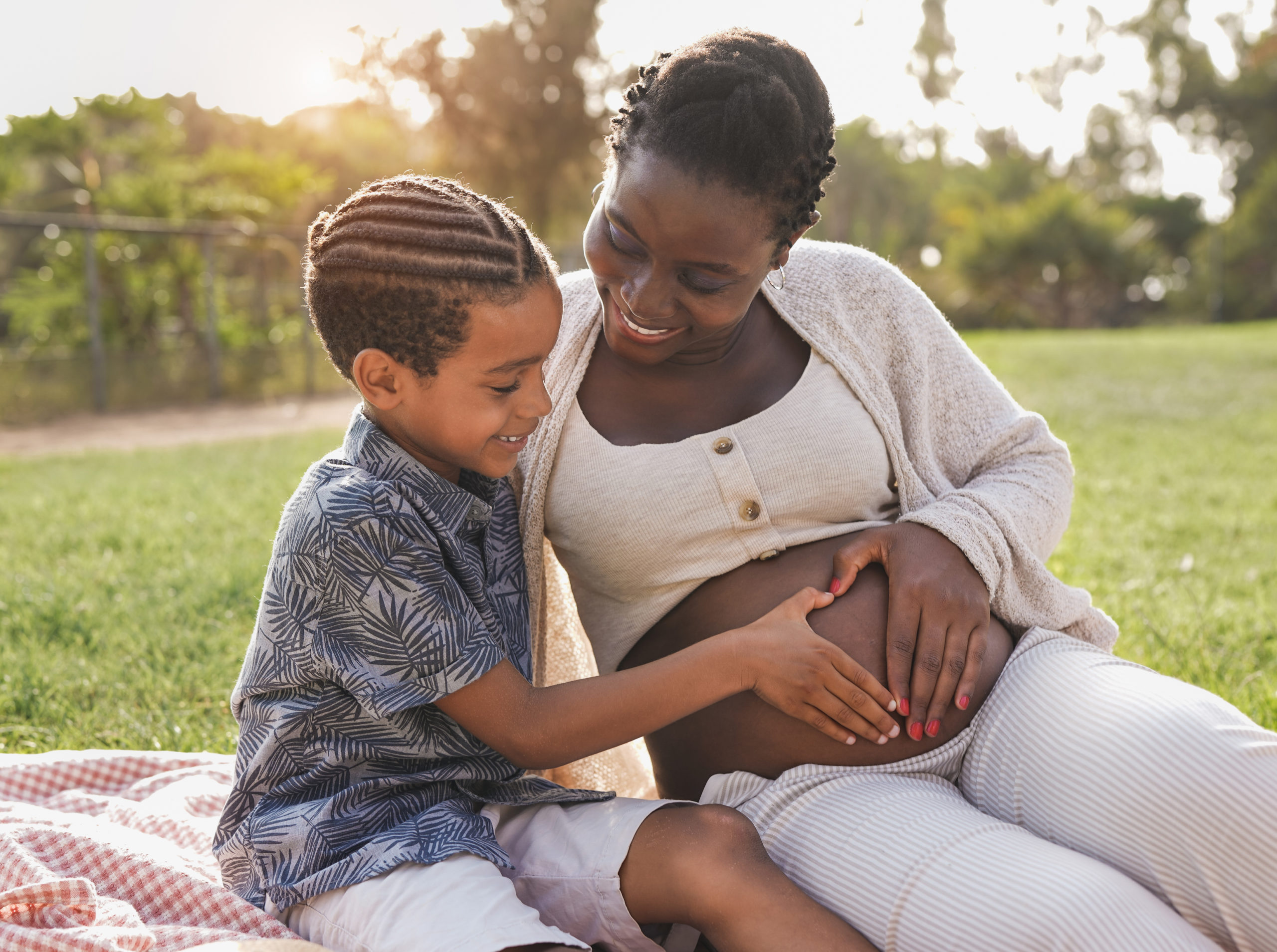 African pregnant mother and mixed race son touching belly