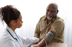 Black female doctor checking measuring pressure on patient's hand