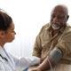 Black female doctor checking measuring pressure on patient's hand