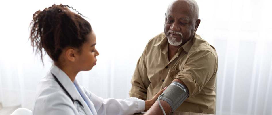Black female doctor checking measuring pressure on patient's hand