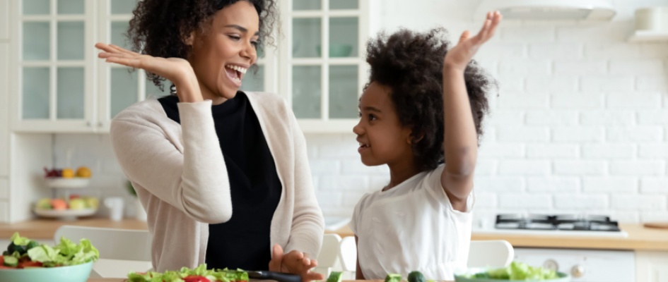 mother and daughter high-fiving in the kitchen