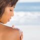 woman looking onto her shoulder with a beach as a background