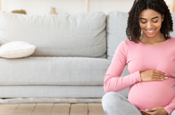 sitting pregnant woman smiling down her stomach