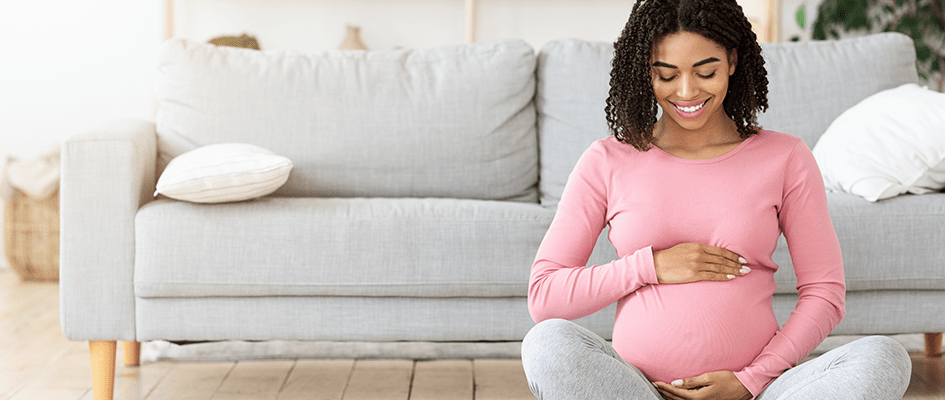 sitting pregnant woman smiling down her stomach