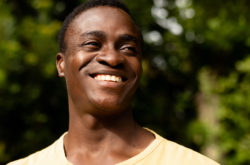 Mid adult african american man smiling while looking away against plants. unaltered, lifestyle, copy space and contented emotion.