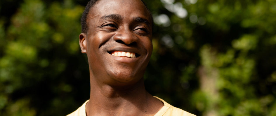 Mid adult african american man smiling while looking away against plants. unaltered, lifestyle, copy space and contented emotion.