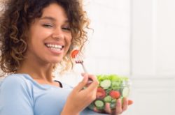 women eating tomato from salad bowl