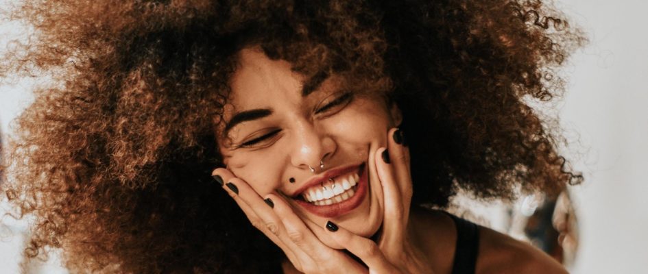 woman smiling with hands on her face