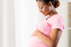 standing pregnant woman observing her belly