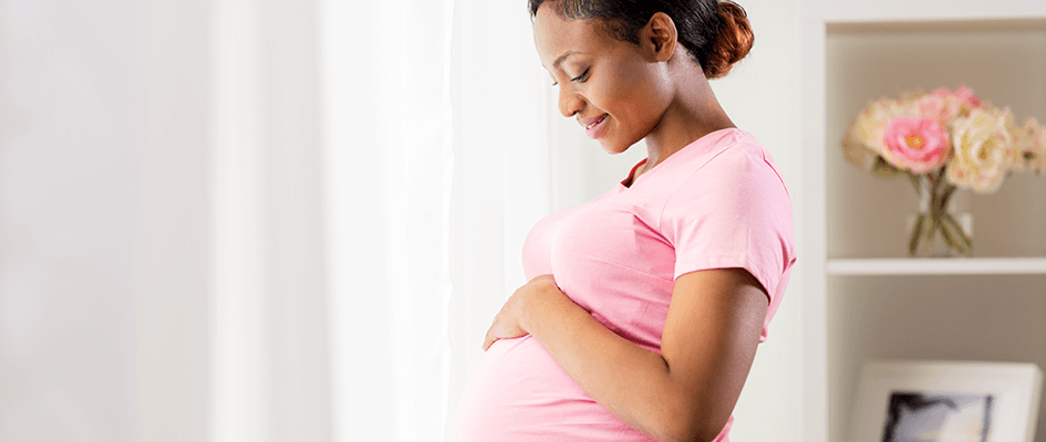 standing pregnant woman observing her belly