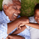 grandfather playing with grandchild on the grass