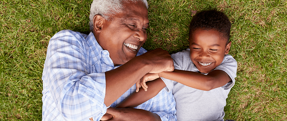 grandfather playing with grandchild on the grass