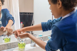 Black boy washing his hands with soap in the bathroom at home to avoid infections coronavirus