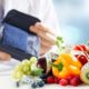 doctor holding bpm tester with fruits and vegetables on tables