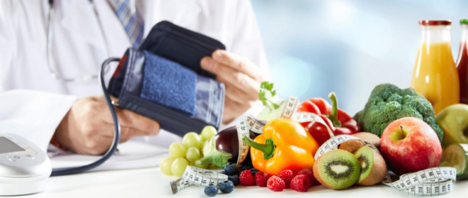 doctor holding bpm tester with fruits and vegetables on tables