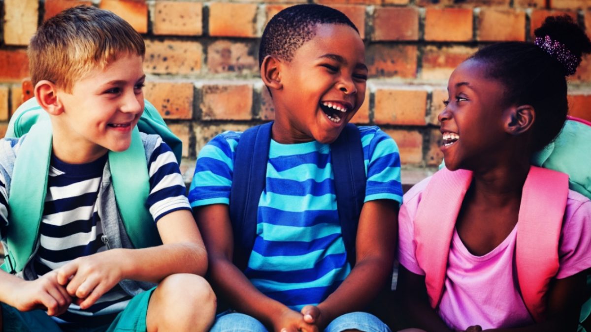 three toddlers laughing with backpack on