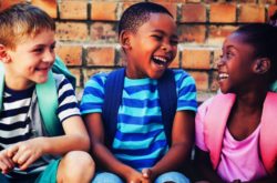 three toddlers laughing with backpack on