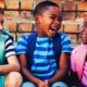 three toddlers laughing with backpack on